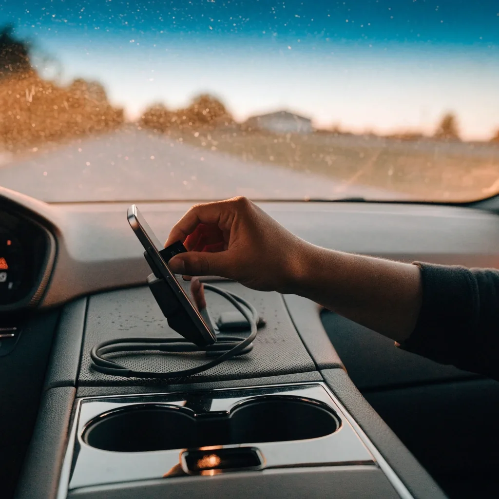A dusty windscreen phone cradle and charging cable seen from the passenger side at dusk